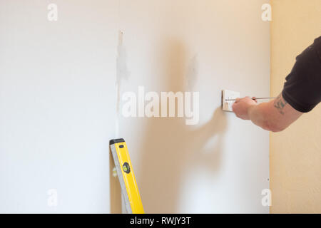 Electrician fitting double socket to stud wall Stock Photo
