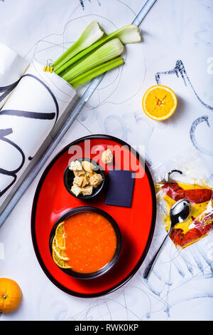 Tomato soup with croutons and cooking ingredients, served in a bowl on white background. View from above, flat lay. Stock Photo