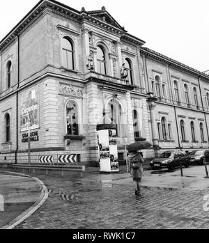 Karlsruhe, Germany - Oct 29, 2017: Young woman with umbrella walking toward Staatliche Kunsthalle Karlsruhe State Art Gallery on Hans-Thoma-Strasse street - black and white Stock Photo