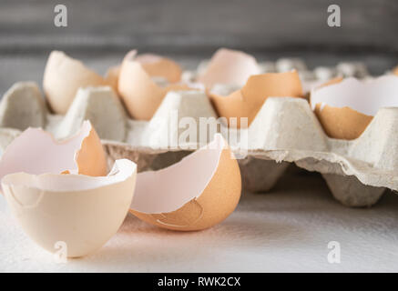 Broken shells from chicken eggs in a box on a white background. Stock Photo
