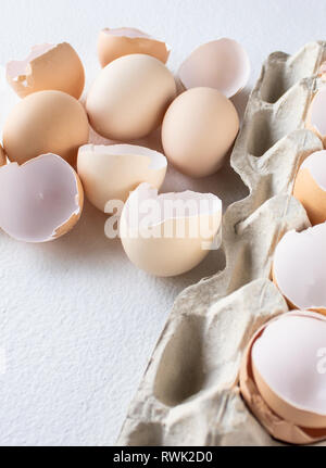 Broken shells of chicken eggs in a box and eggs on a white background. Stock Photo