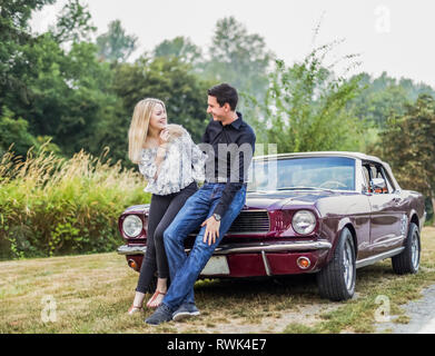 A young couple standing with a vintage sports car; Bothell, Washington, United States of America Stock Photo