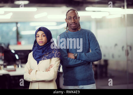 portrait of black muslim female software developer standing together with her african american male colleague at modern startup office Stock Photo