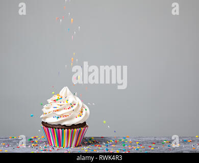 A Cupcake being decorated with colorful Sprinkles. Stock Photo