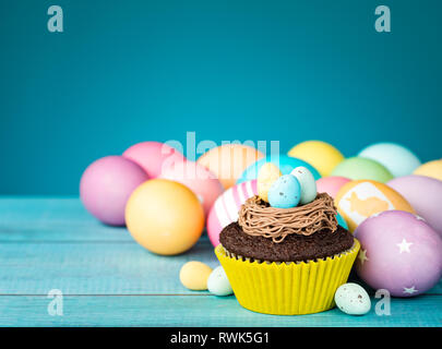 Colorful Easter Eggs and cupcake with nest on a blue background. Stock Photo