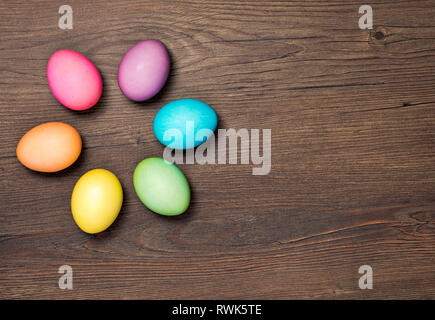 Colorful Easter Eggs arranged on a wooden background. Stock Photo