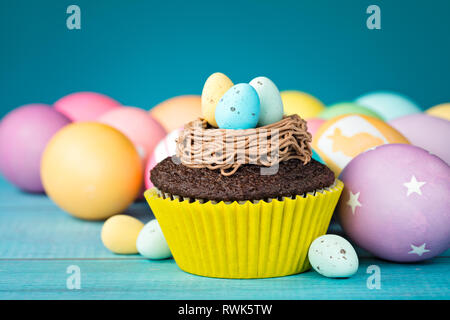 Colourful Easter Eggs and cupcake with nest on a blue background. Stock Photo