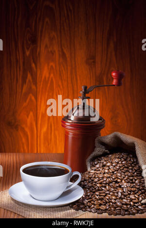 Cup of coffee with roasted beans and coffee grinder on wooden  background. Stock Photo