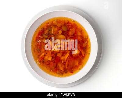 Bowl with chicken, beetroot and other vegetables soup. Perfect bright broth in italian minestrone style, isolated on white. Top view or flat lay. Stock Photo