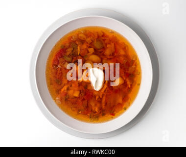 Bowl with chicken, beetroot and other vegetables soup. Perfect bright broth in italian minestrone style, isolated on white. Top view or flat lay. Stock Photo
