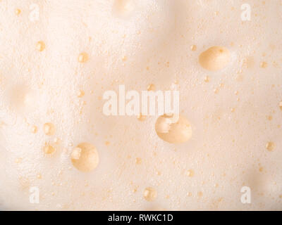 Foam texture extreme close up as background. Milkshake or cappucino foam with bubbles macro shoot. Copy space for text. Stock Photo