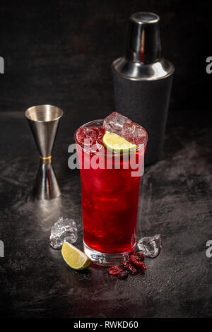 Refreshment alcoholic red cranberry and lime cocktail with ice on black background Stock Photo