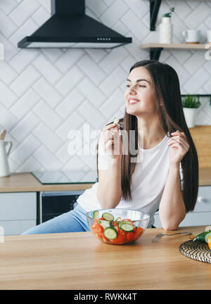 Young brunette woman eating fresh salad at home Stock Photo