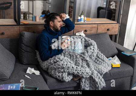 Nice young man feeling his high temperature Stock Photo