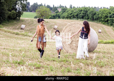 Friends and girl in field of hay bales, Città della Pieve, Umbria, Italy Stock Photo