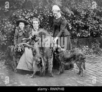 A Victorian or Edwardian group photograph of a young girl, two female adults and what looks like four Flat-coated Retriever dogs. Stock Photo