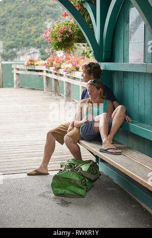Young couple relaxing on pier bench, Lake Annecy, Annecy, Rhone-Alpes, France Stock Photo