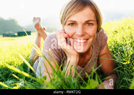 Woman lying down on grass in countryside Stock Photo