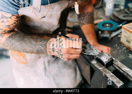 Axe maker using steel grinder in workshop Stock Photo