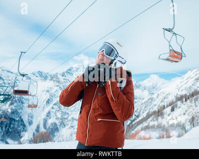 Young woman skier fastening helmet in snow covered landscape, Alpe Ciamporino, Piemonte, Italy Stock Photo