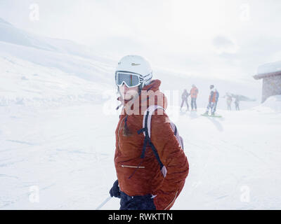 Young female skier wearing helmet and ski goggles on ski slope,  Alpe Ciamporino, Piemonte, Italy Stock Photo