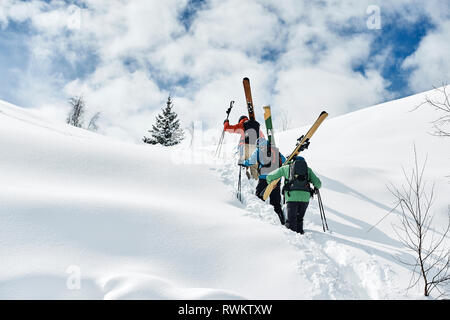 Male skiers trudging up snow covered mountain, rear view, Alpe-d'Huez, Rhone-Alpes, France Stock Photo