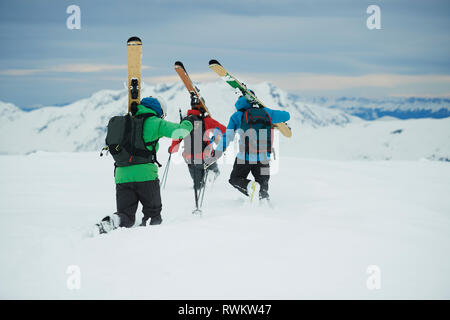 Landscape with three male skiers trudging toward mountain, rear view, Alpe-d'Huez, Rhone-Alpes, France Stock Photo