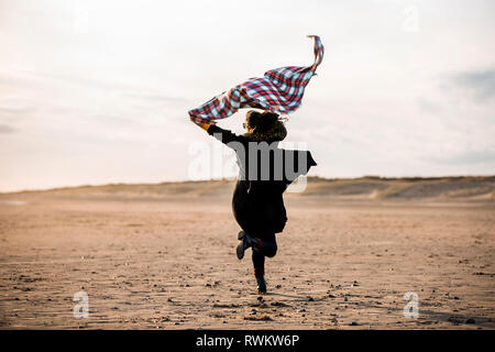 Woman running with beach blanket Stock Photo