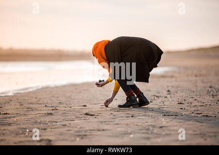 Woman collecting pebbles on beach Stock Photo