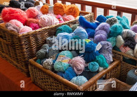 A close up of two wicker baskets of knitting wool for sale, mostly blues and oranges Stock Photo