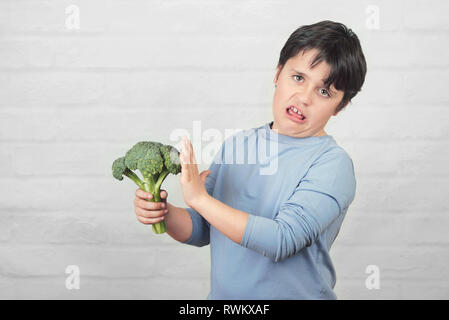 Child do not like to broccoli against brick background Stock Photo