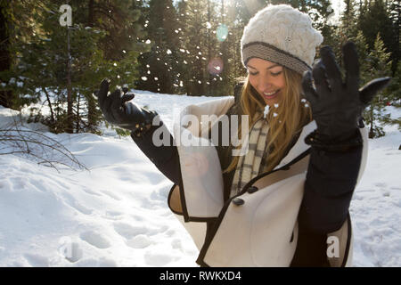 Young woman playing with snow in winter forest, Twain Harte, California, USA Stock Photo