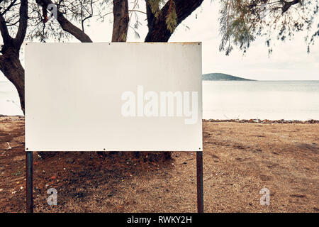 Blank empty white sign post on the beach near the sea on a seaside background Stock Photo