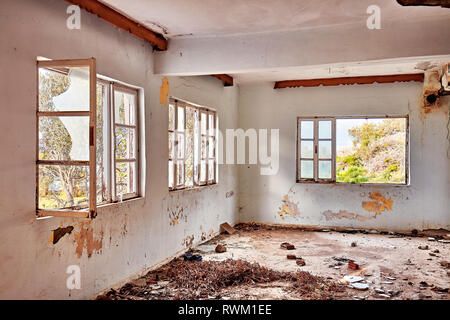 Interior of an old abandoned ruin house with white cracked walls and glassless broken window frames Stock Photo