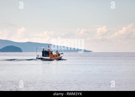 Fishing boat carrying two fisherman sailing over the calm sea in winter time in Gumusluk, Bodrum, Turkey. Stock Photo
