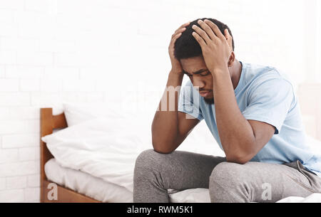 Young sad man touching his head and keeping eyes closed Stock Photo