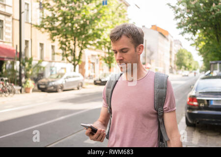 Male freelancer entrepreneur using his cellphone, Berlin, Germany Stock Photo