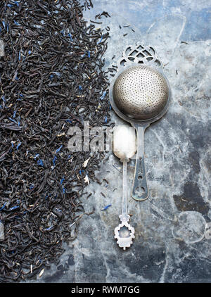 Tea leaves, tea strainer and silver spoon Stock Photo