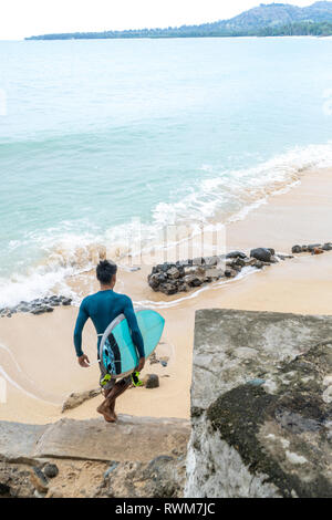 Surfer with surfboard on beach, Pagudpud, Ilocos Norte, Philippines Stock Photo