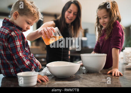 Children watching mother pour honey into bowl Stock Photo