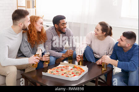 Friends eating pizza, having little party at home Stock Photo