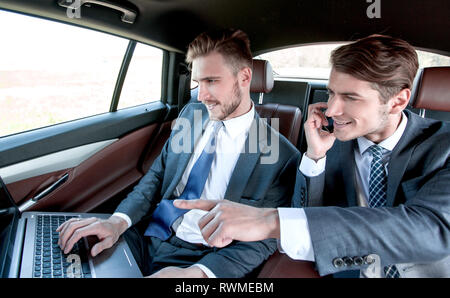 two businessmen use a laptop in the car Stock Photo