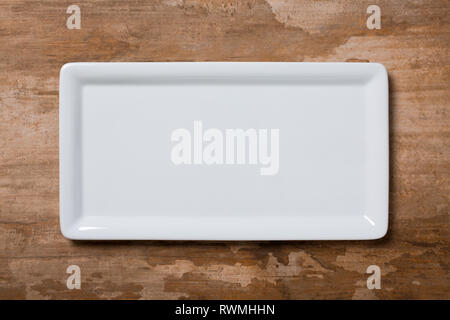 Empty white cornered plate on brown wooden background, top view Stock Photo