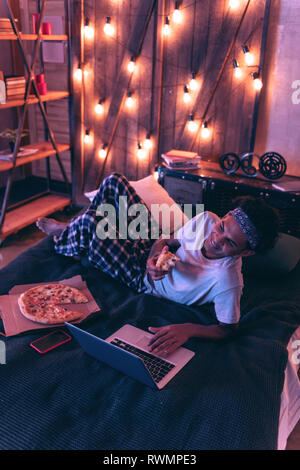 Smiling guy ordering pizza for dinner for not to be distracted from work. Stock Photo