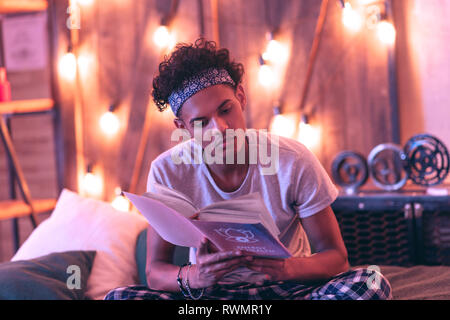 Pensive guy looking for answers to his questions in the book about energy and spirit. Stock Photo