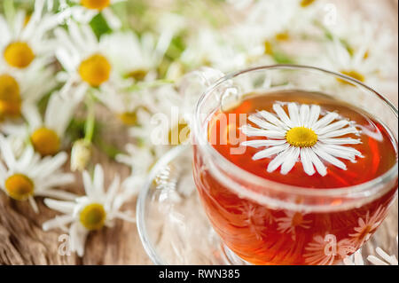 A clear Cup of medicinal chamomile tea on an old wooden table. Health and healthy lifestyle concept. Stock Photo