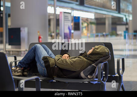 Passenger young man sleeping while waiting the plane at airport passenger terminal Stock Photo