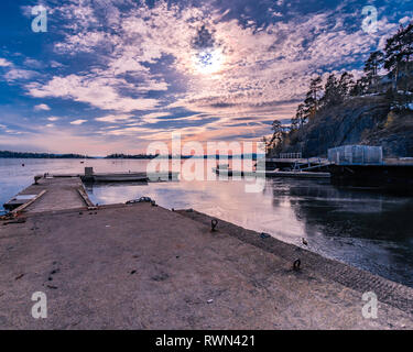 Small pier with couple of boats on this half frozen sea with amazing and colorfull look Stock Photo