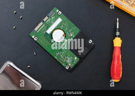 hard disk drive and set of screwdriver at black background. repair hdd after diagnostics. data maintenance after virus attack. Stock Photo