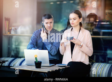 Two businesspeople working together in a local cafe. Businesspeople working together on a cafe terrace. Attractive businesswoman drinking coffee Stock Photo